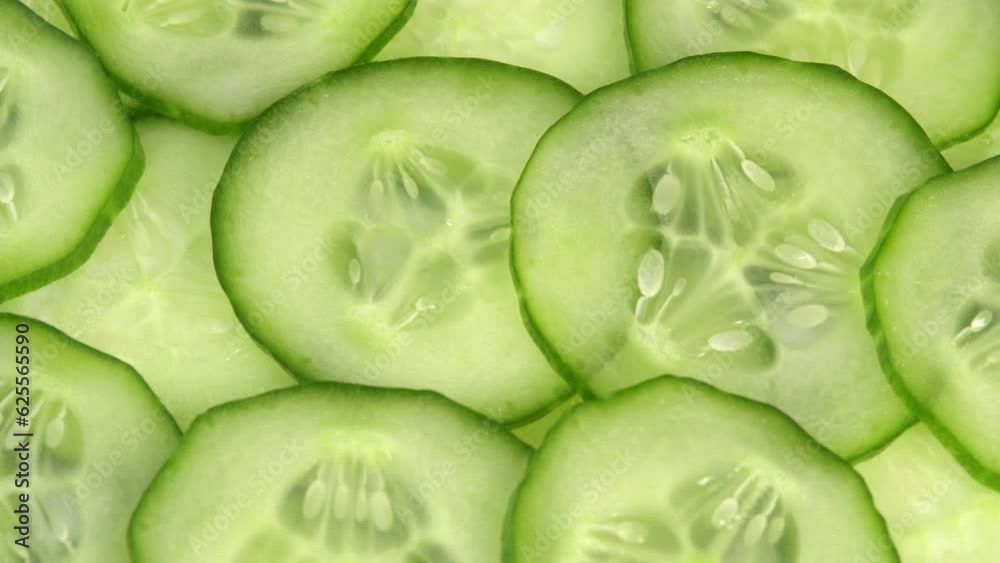 Top view fresh cucumber cut into slices rotate. Background of chopped cucumber slices for cooking show, restaurant, cafe, fast food. Moisturizing the skin and smoothing wrinkles Top view fresh cucumber cut into slices rotate. Background of chopped cucumber slices for cooking show, restaurant, cafe, fast food. Moisturizing the skin and smoothing wrinkles