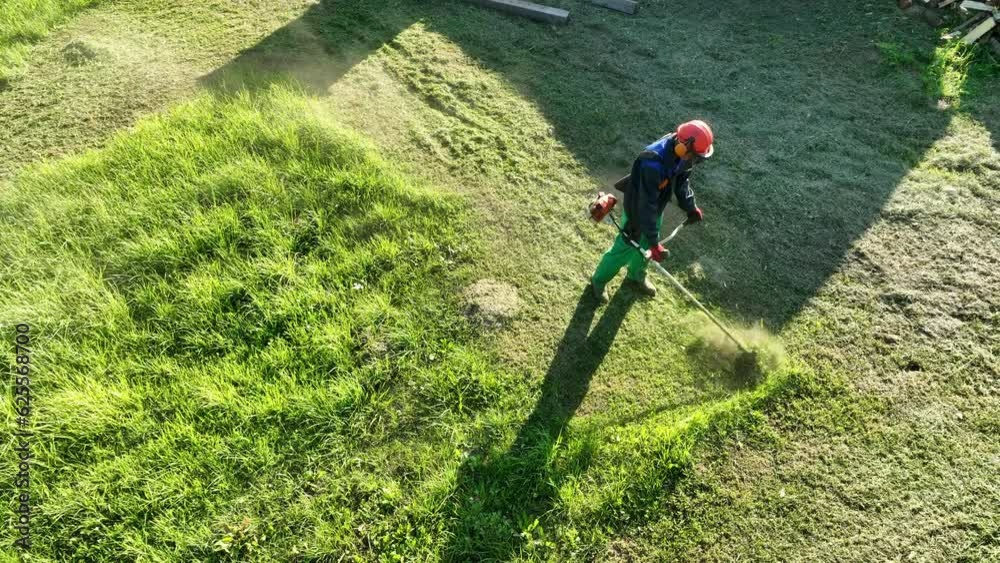 Gardener mows weeds grass. Man cutting grass in yard by using string trimmer. Worker lawn mower cutting green garden. Lawn mowing machine. Grass Trimmer and Grass Cutter. lawn maintenance service. Gardener mows weeds grass. Man cutting grass in yard by using string trimmer. Worker lawn mower cutting green garden. Lawn mowing machine. Grass Trimmer and Grass Cutter. lawn maintenance service.
