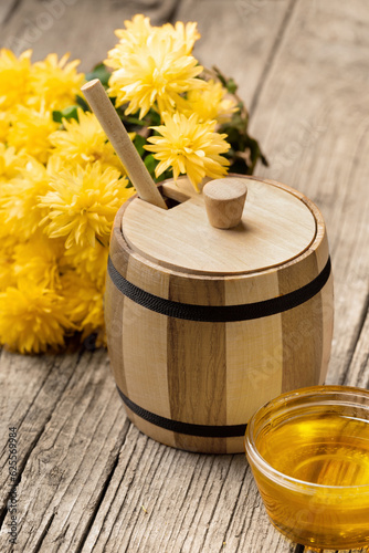 Wooden barrel and bowl with flower honey on an aged wooden background.