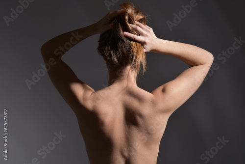 Belle femme au dos nu avec les mains dans les cheveux photo