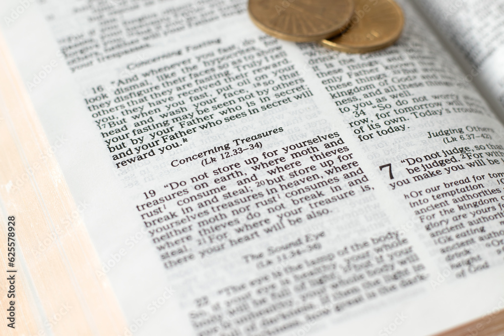 Obraz premium Biblical verses concerning treasures in open holy bible with golden coins. Christian teaching for serving God versus money, biblical concept. Selective focus.