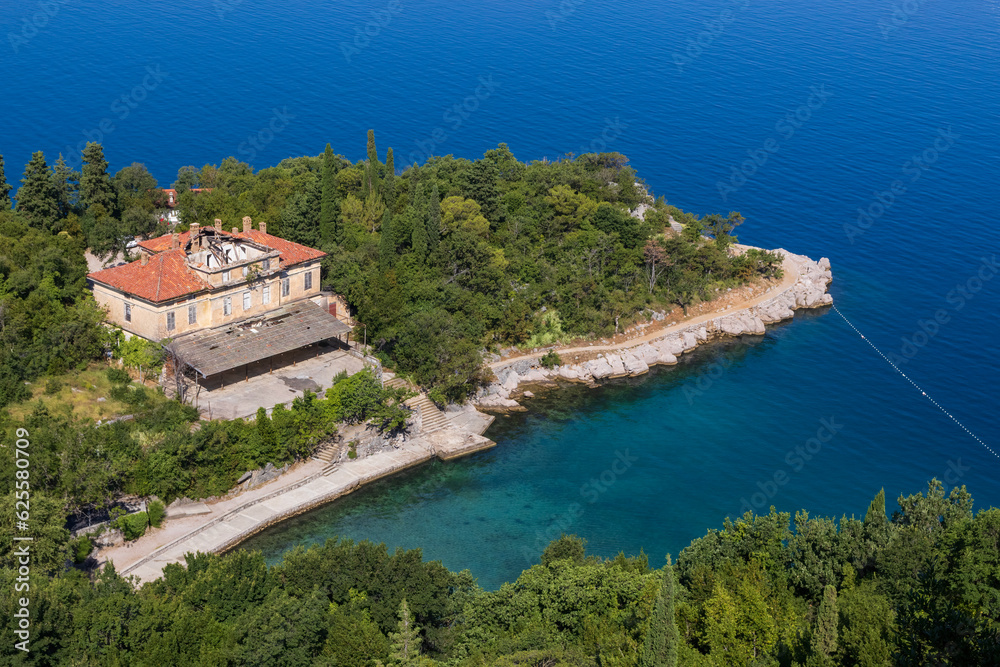 Old hotel building on island in blue sea with beach. Travel destination background, Krk, Croatia