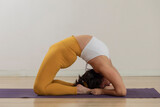 Young mexican woman practicing yoga does a backbend on the floor