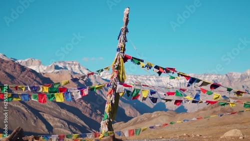 Slow motion shot of prayer flags waving in the wind in front of the snow covered Himalayan mountains at Kunzum Pass on the way to Kaza from Manali in Himachal Pradesh, India. Prayer flags at Kunzum. 