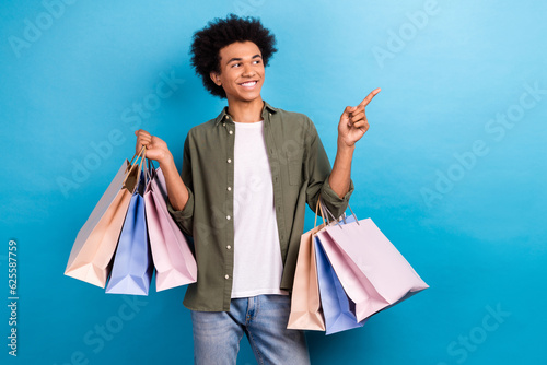Photo of young student man enjoy shopping pointing finger looking empty space promo code asos web store isolated on blue color background