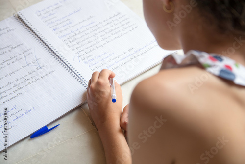 Close up de manos de estudiante escribiendo en una libreta en vacaciones. Zurdos.