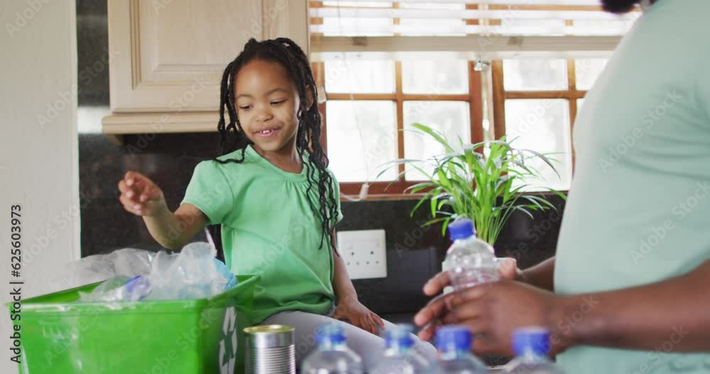 African american father and daughter sorting plastic bottles for recycling in kitchen African american father and daughter sorting plastic bottles for recycling in kitchen