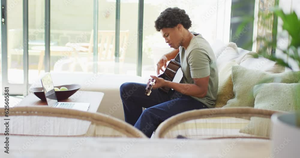 African american man plays guitar and singing, using laptop at home African american man plays guitar and singing, using laptop at home
