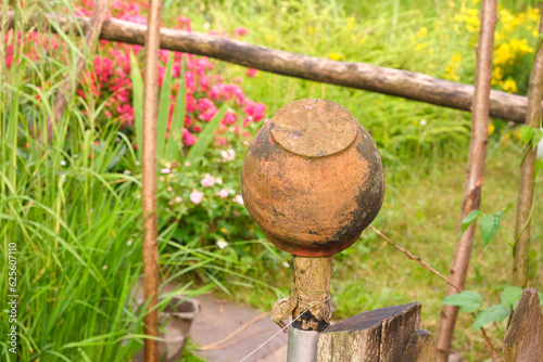 ceramic pot on the fence in the country, grass and flowers