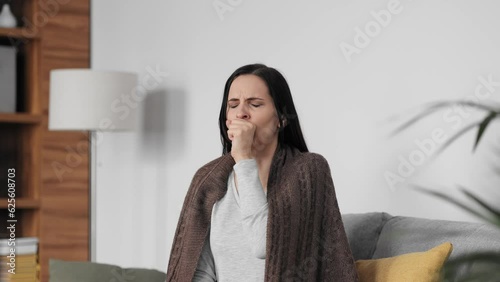Portrait of ill young woman at home having cough and sore throat. First symptoms of cold and flu virus, pneumonia, bronchitis and respiratory tract infection. Seasonal virus disease. photo