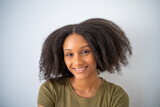 Cute African American girl with Afro hairstyle smiling and looks at camera. Portrait of female black positive teenager.