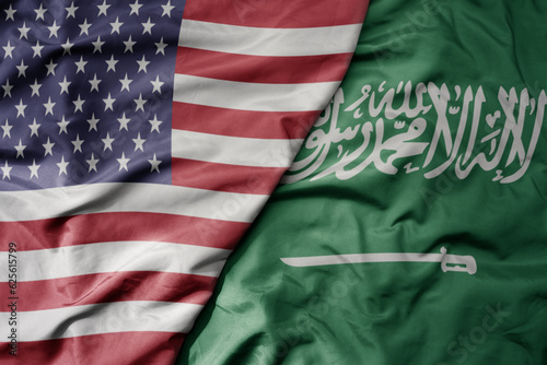big waving colorful flag of united states of america and national flag of saudi arabia .
