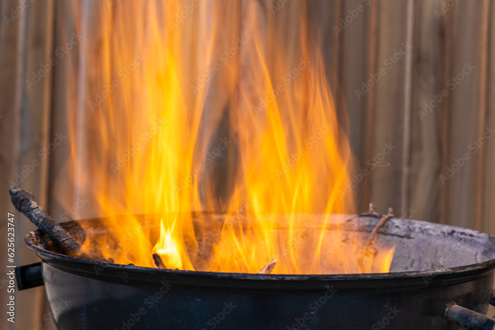 Black metal round barbeque with fire for a picnic is in the terrace Black metal round barbeque with fire for a picnic is in the terrace