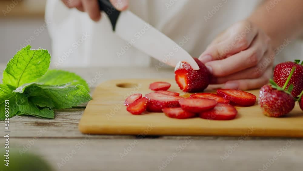 Start day with strawberries. Side view of woman's hand slicing fresh juicy strawberries in kitchen. Red strawberry fruit on wooden cutting board. Vegetarian, vegan diet