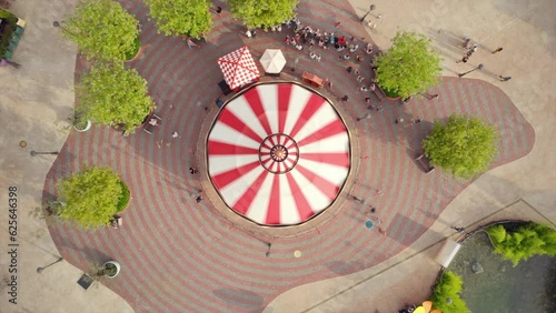 Top down shot of Carousel spinning in timelapse, aerial view of amusement park with people walking around сolorful playground, revealing entertainment attractions.