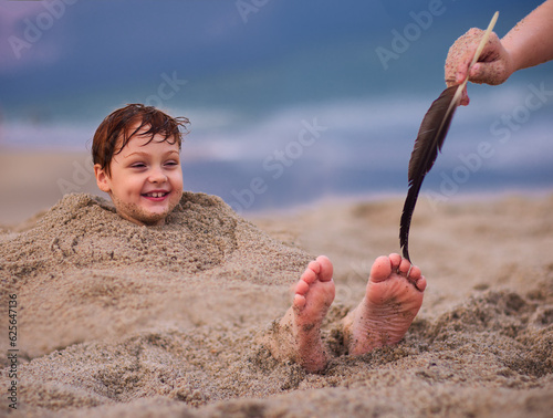 Φωτογραφία tickling kid's feet in a sand