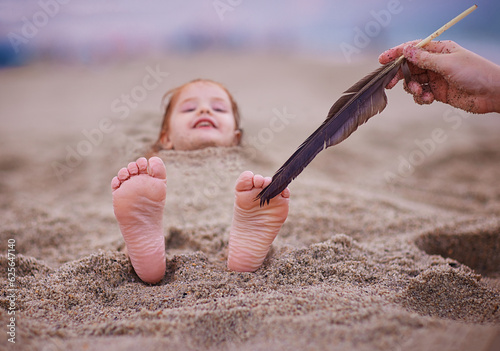фотографія tickling happy baby's feet in a sand