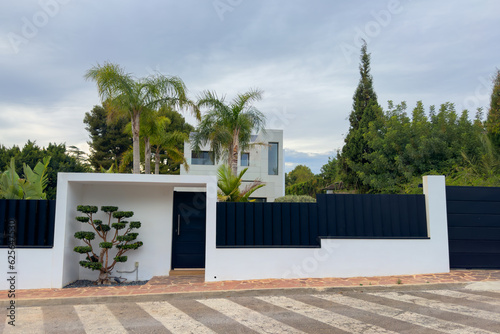 Villa in Los Monasterios Urbanization residential area. Design house and luxury facilities. Fence at a suburb house. Construction of modern house near coastline. Villa under construction in mountains