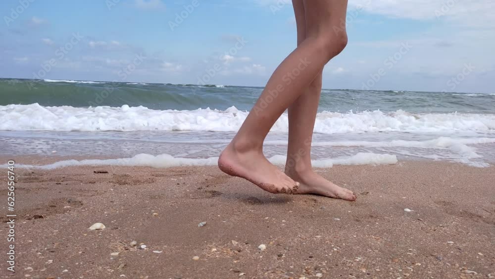 Close-up of bare male feet walking along the sandy coast on a summer day. Legs of a walking man on a sandy beach against the background of the sea, slow motion. Close-up of bare male feet walking along the sandy coast on a summer day. Legs of a walking man on a sandy beach against the background of the sea, slow motion.