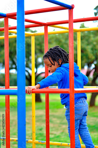  beautiful young black African boy with dreadlocks playing in a park .