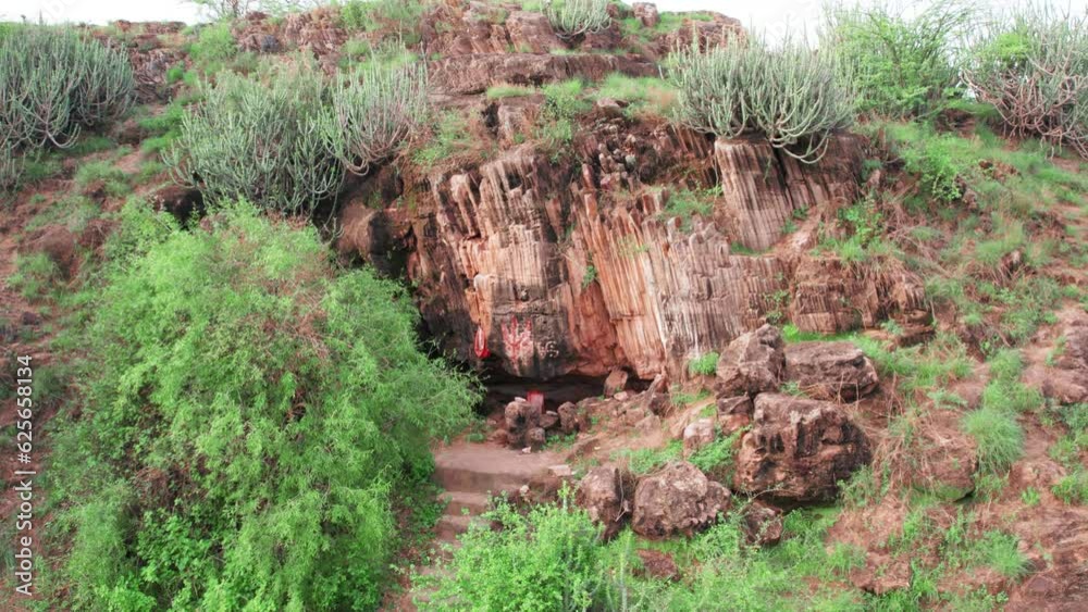4K aerial view of Unique volcanic basalt column formation and small temple in cave in Kodaki village, Kutch, India. Result of an ancient volcanic fissure eruption. Natural wonder. Symmetrical geometri