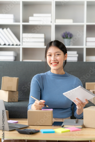 Young business owner woman prepare parcel box and standing check online orders for deliver to customer on tablet, laptop Shopping Online concept.