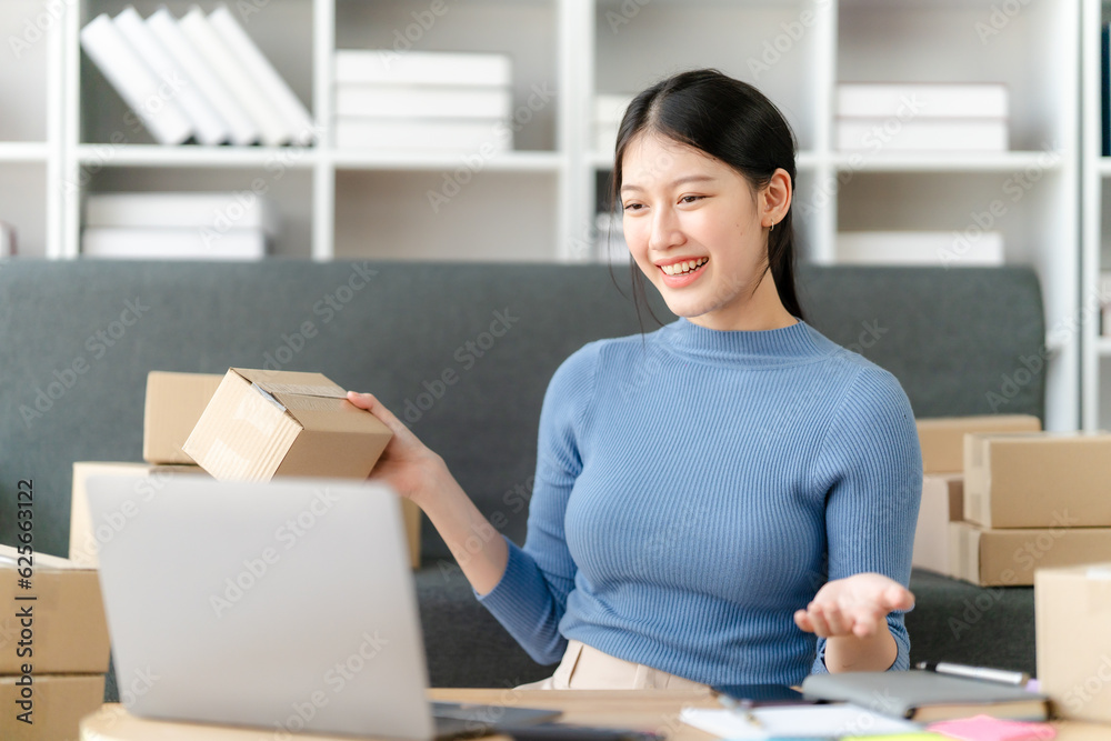 Young business owner woman prepare parcel box and standing check online orders for deliver to customer on tablet, laptop Shopping Online concept.