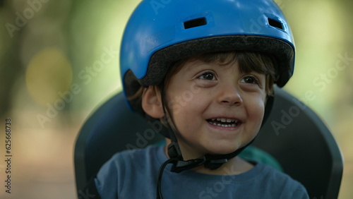 Child wearing bike helmet portrait kid sitting in bike back seat © Marco