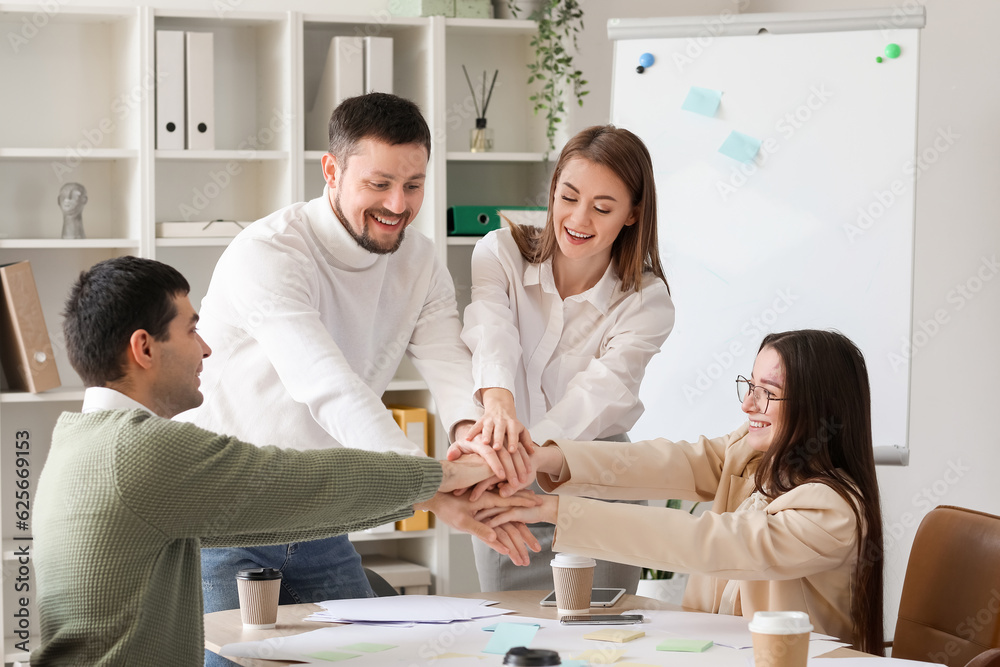 Group of business colleagues putting hands together in office Group of business colleagues putting hands together in office