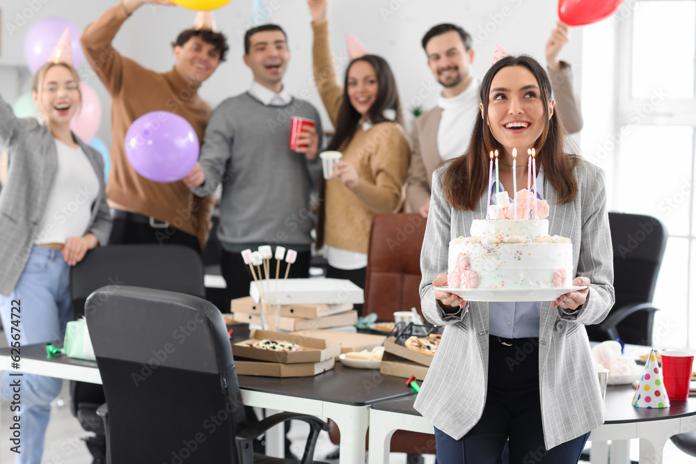 Young woman with Birthday cake making wish at party in office Young woman with Birthday cake making wish at party in office