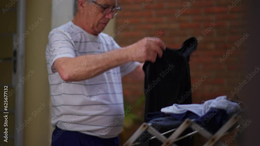 Casual Portrait of Independent Elderly Man Engaging in Weekly Routine, Hanging Clothes to Dry in Humble Home Backyard Casual Portrait of Independent Elderly Man Engaging in Weekly Routine, Hanging Clothes to Dry in Humble Home Backyard