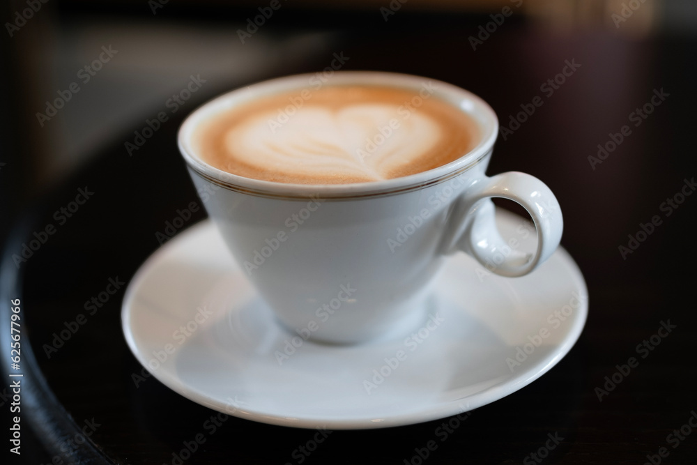 Cappuccino in white cup on saucer with latte art on top Cappuccino in white cup on saucer with latte art on top