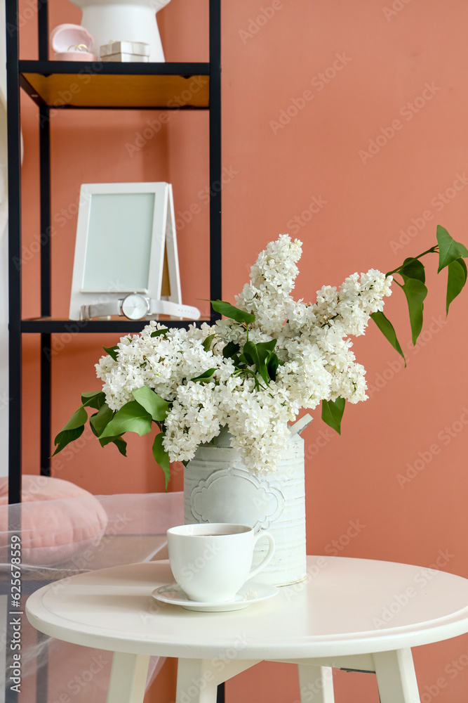 Fototapeta premium Vase with lilac flowers and cup of coffee on table in dressing room