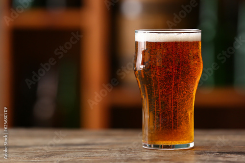 Glass of beer on table in b...