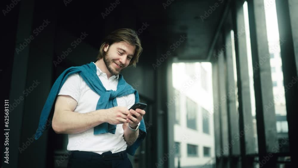 Businessman stand in the city center street uses phone, texting, browsing financial news. Successful male proud ceo smiling during cellular messaging. Handsome bearded Startup Businessman Businessman stand in the city center street uses phone, texting, browsing financial news. Successful male proud ceo smiling during cellular messaging. Handsome bearded Startup Businessman