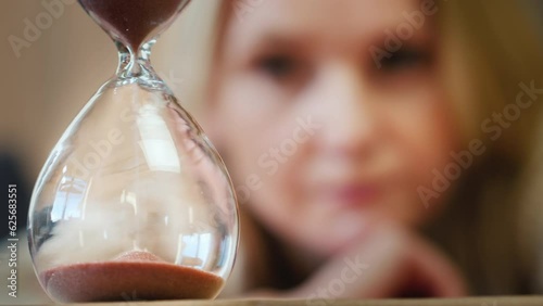 Thoughtful middle-aged woman looks at the sand in an hourglass photo