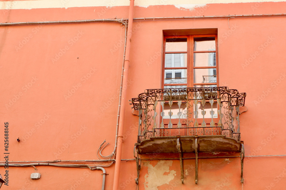 Vintage metallic balcony on the weathered scratched wall in Cagliari, Sardinia, Italy. Vintage architecture. Old fashioned living