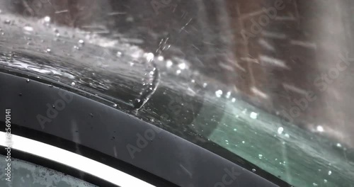 Top of a car and windshield being hit by rainy hail storm. Concept: Vehicle Hail Damage Insurance Coverage photo