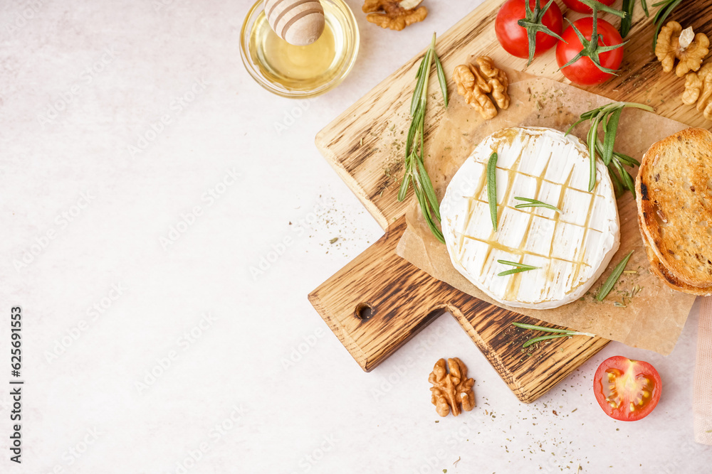 Fototapeta premium Wooden board with tasty baked Camembert cheese on light background