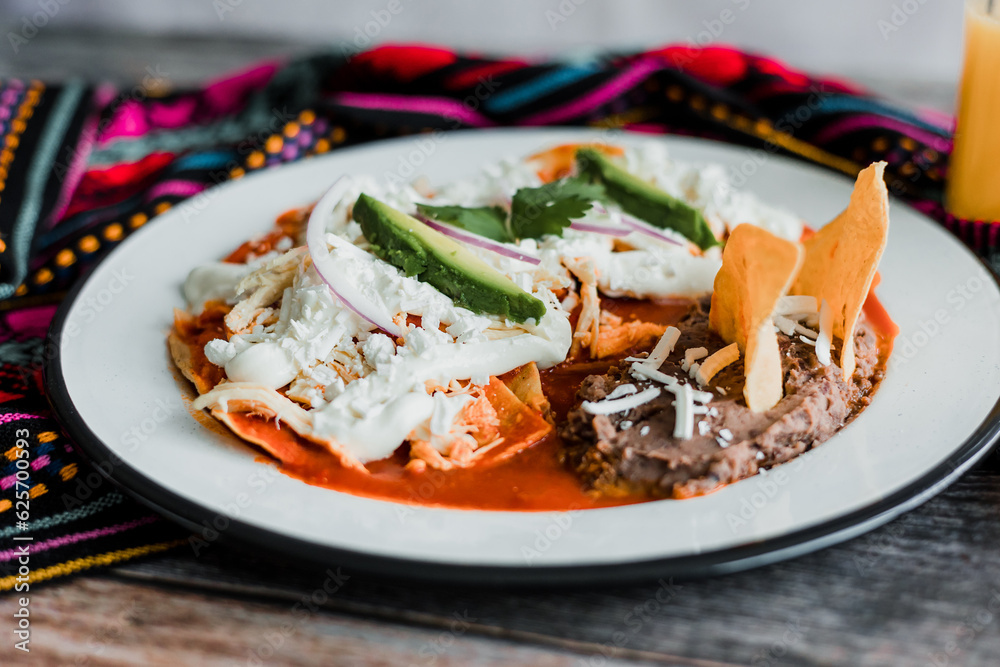 Mexican chilaquiles food with spicy red sauce, chicken and avocado traditional breakfast in Mexico Latin America Mexican chilaquiles food with spicy red sauce, chicken and avocado traditional breakfast in Mexico Latin America