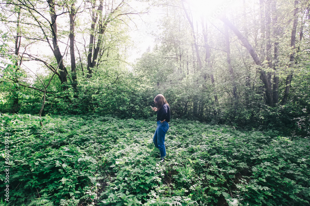 Spring landscape. Teenager girl walks in the wild forest in the countryside.