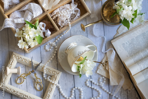 Cup of aromatic jasmine tea and fresh flowers on wooden table, flat lay