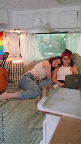 Two beautiful hippie girls are lying on the bed inside the trailer, with one of them resting her head on the other's shoulder. photo