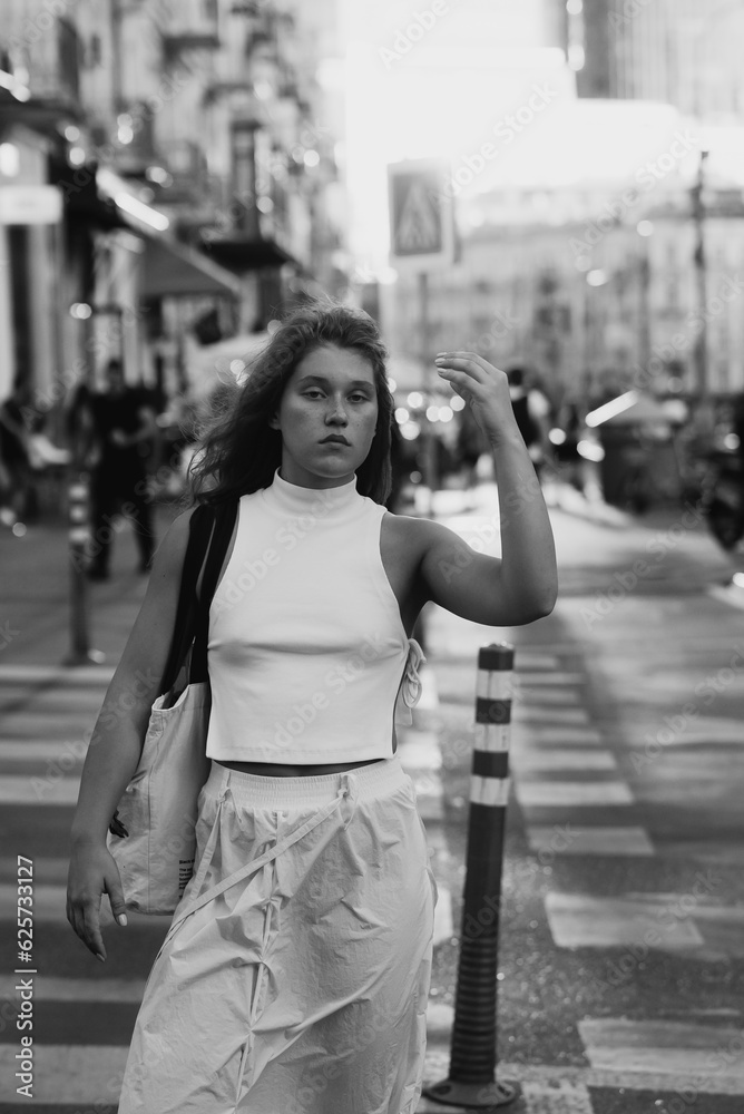 A fashionable girl in white attire with curly hair on the city streets.