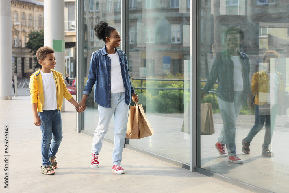 Fototapeta premium Family shopping. Happy mother and son with purchases near mall outdoors