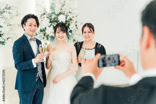 披露宴・パーティーで新郎新婦とスマホで写真を撮る女性
