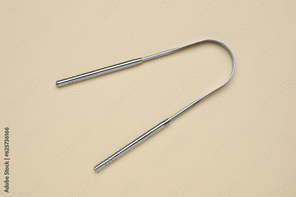 Metal tongue cleaner on beige background, top view Metal tongue cleaner on beige background, top view