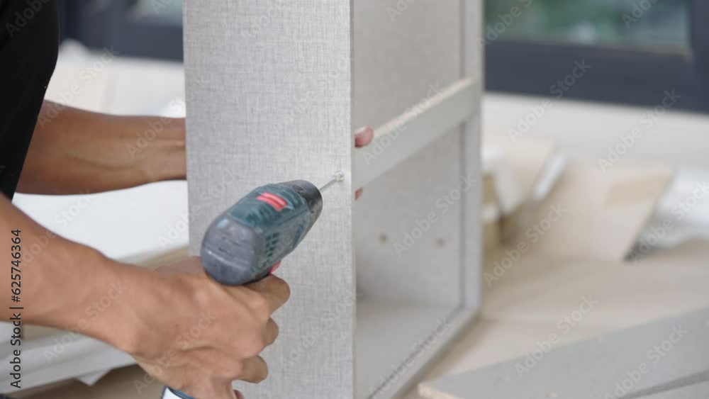 Close up worker man assembling furniture in a woodworking workshop with a of drilling into wood with screw in the house Close up worker man assembling furniture in a woodworking workshop with a of drilling into wood with screw in the house