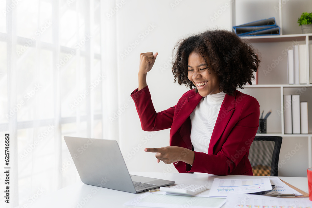 Obraz premium African american girl working at office with laptop and financial document calculator excited about success with arms raised and to celebrate victory with smile.