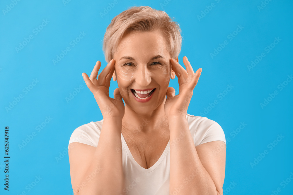 Fototapeta premium Mature woman with marked face for filler injection on blue background, closeup